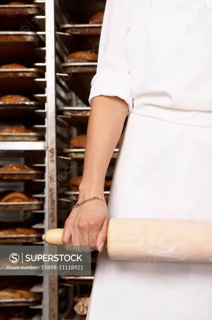 Hispanic baker holding rolling pin in bakery