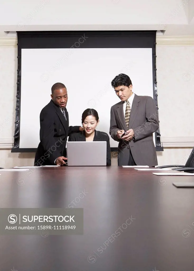Business people using laptop at conference table