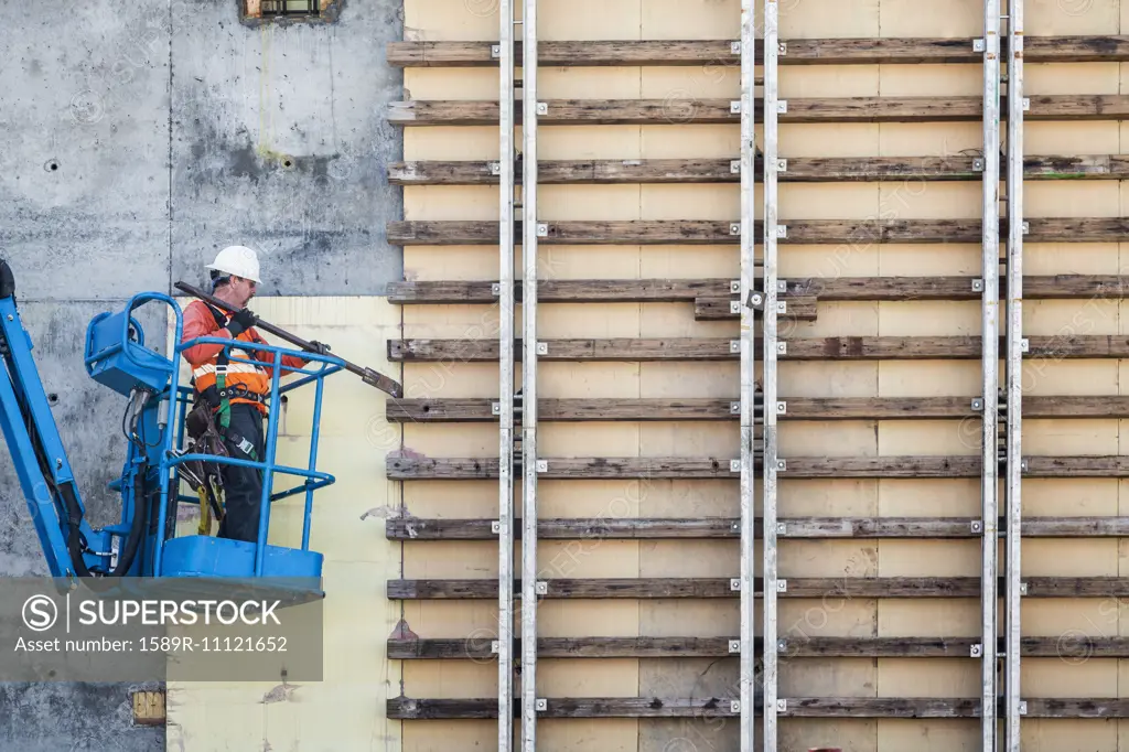 Caucasian worker on boom lift working on construction site