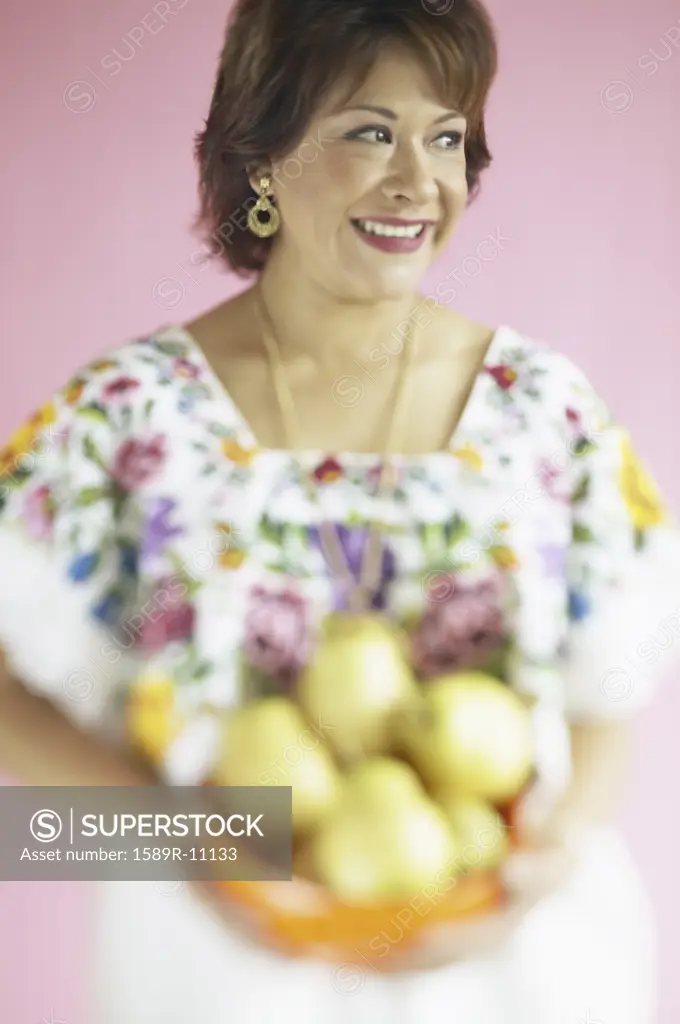 Mid adult woman smiling holding fruits