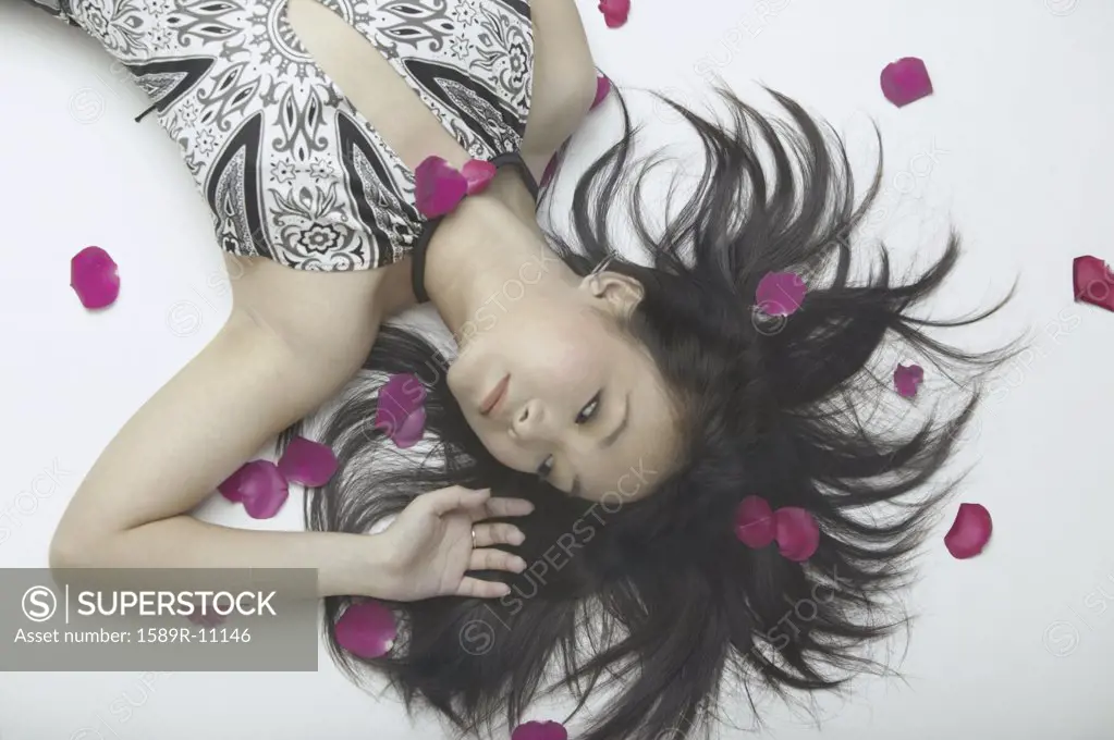 Young woman lying on the floor with rose petals around her