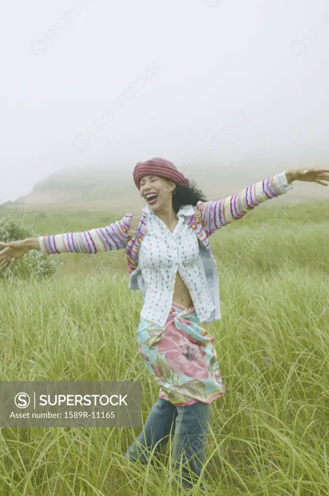 Young woman in a field with her arms stretched out