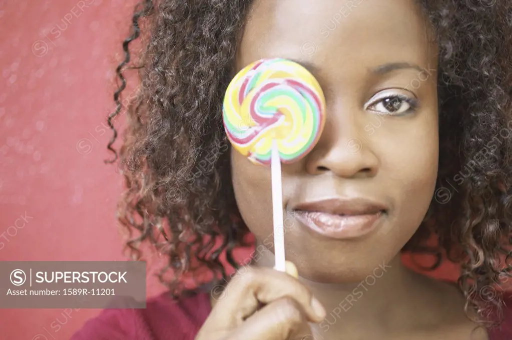 Woman holding lollipop in front of her eye