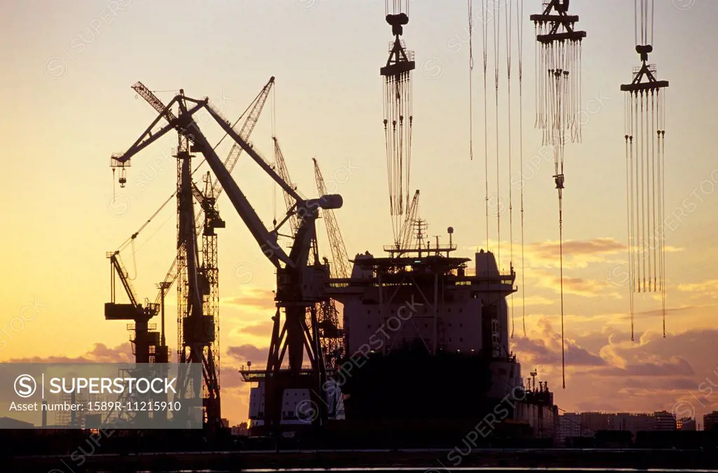 Cranes and a Tanker Moored at a Harbour at Sunset