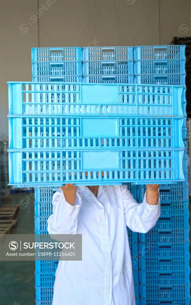 Woman holding crates in front of face