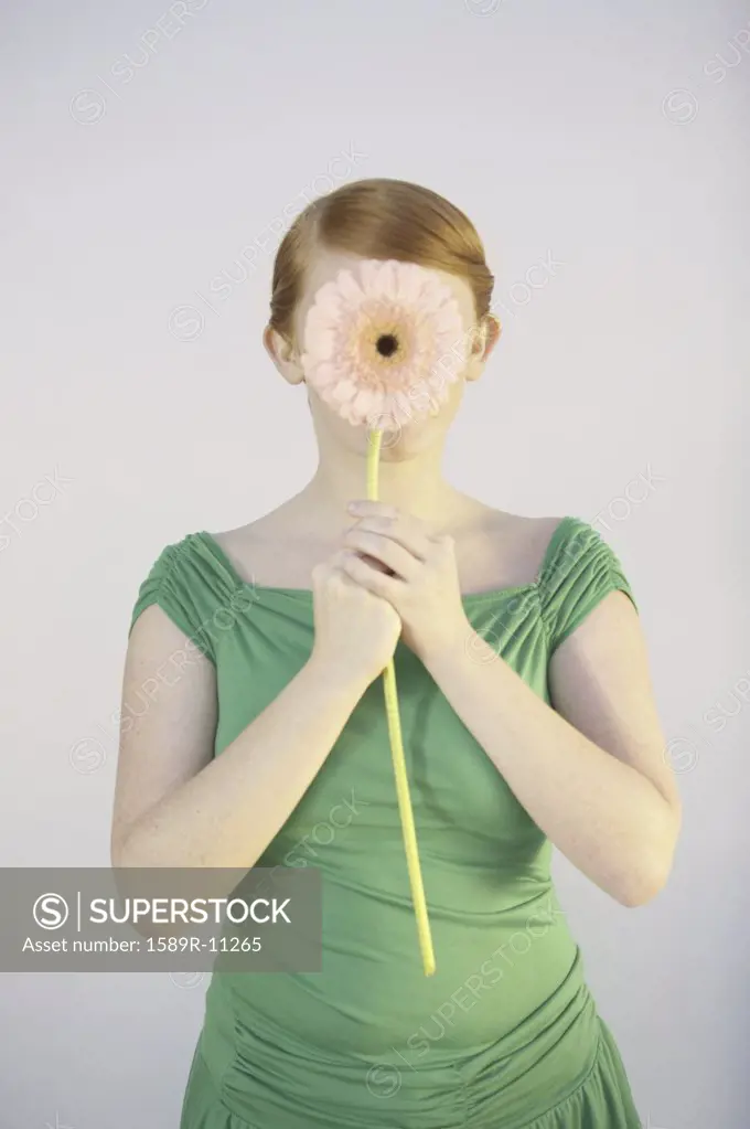 Young woman covering her face with a flower