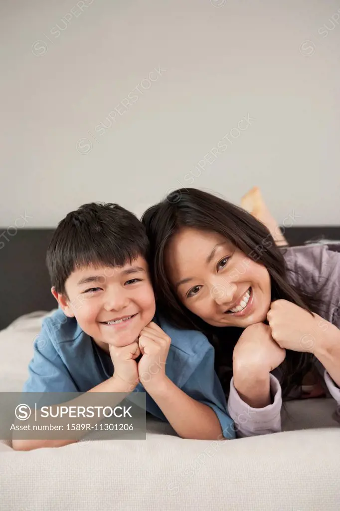 Asian mother and son laying on bed