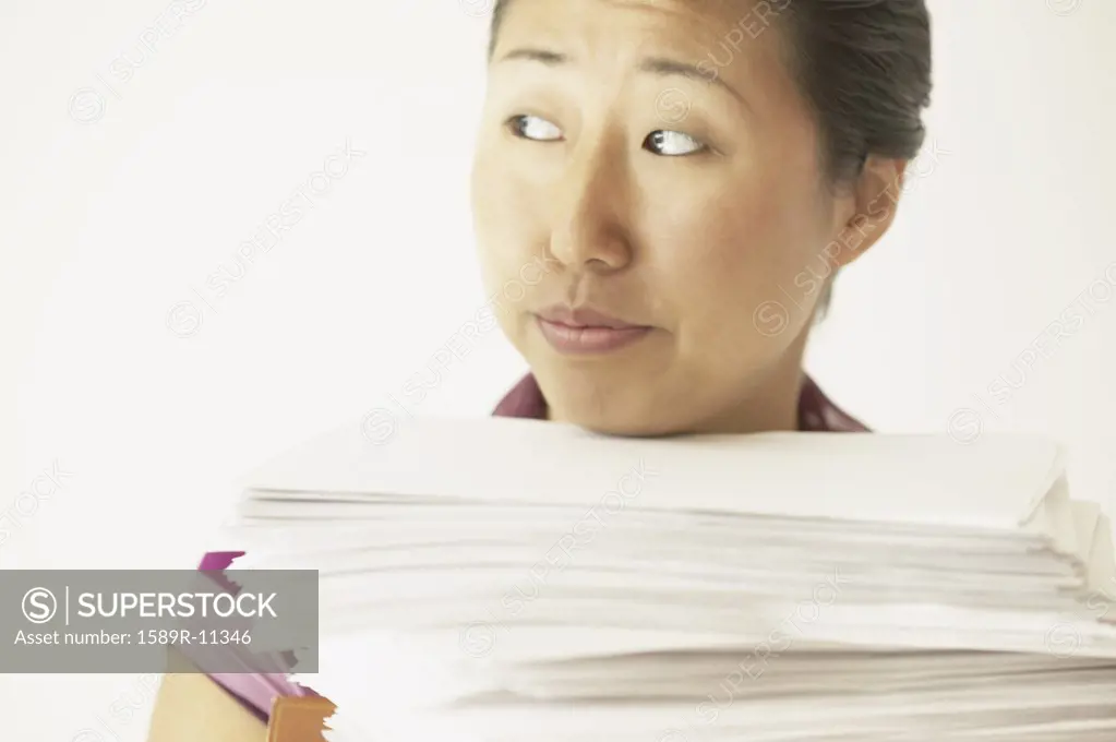 Young woman carrying a stack of papers
