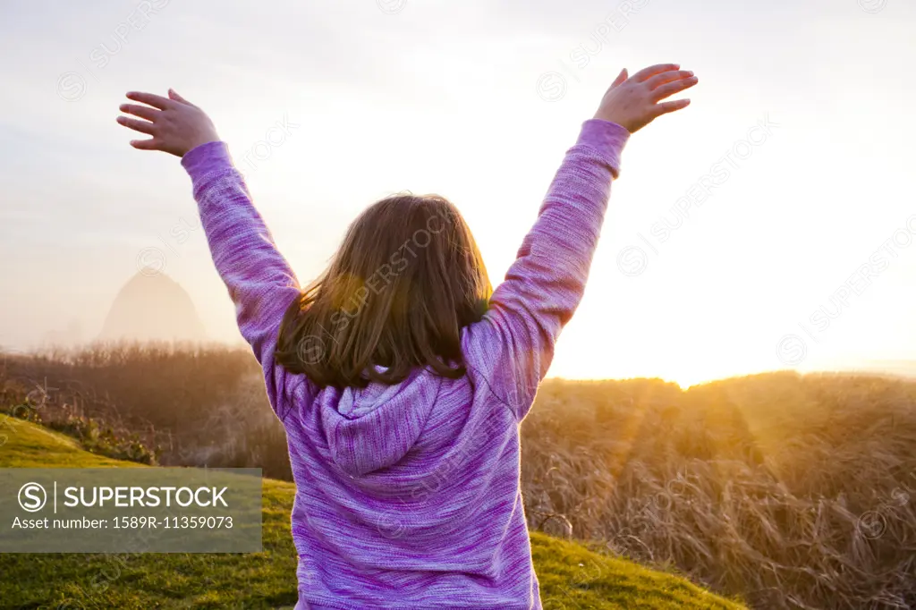 Caucasian girl cheering on rural cliffs
