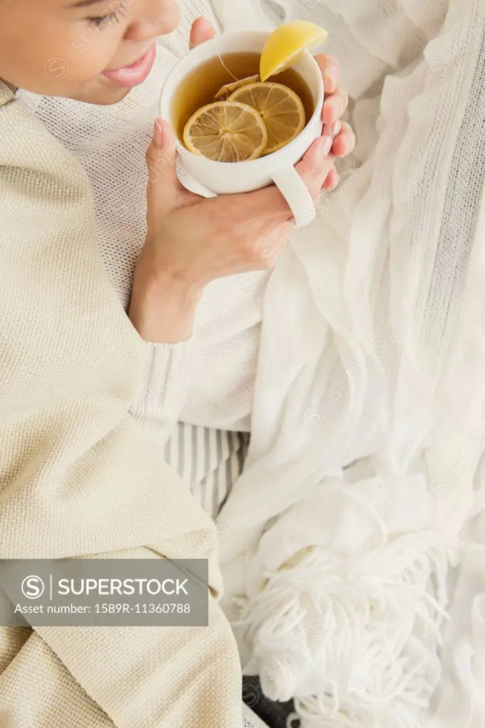 Black woman drinking cup of tea with lemon