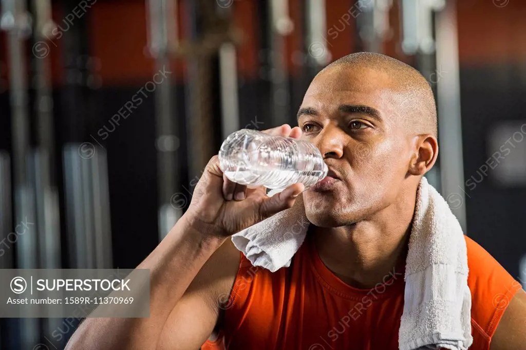 Black man drinking water in gym