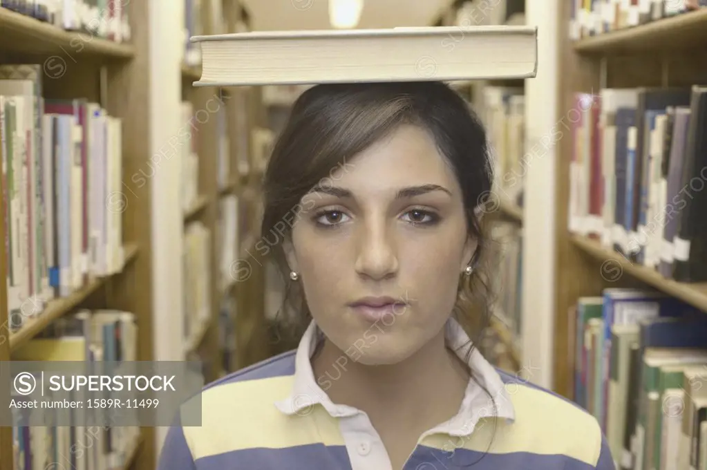 Closeup of teenage girl with book on head