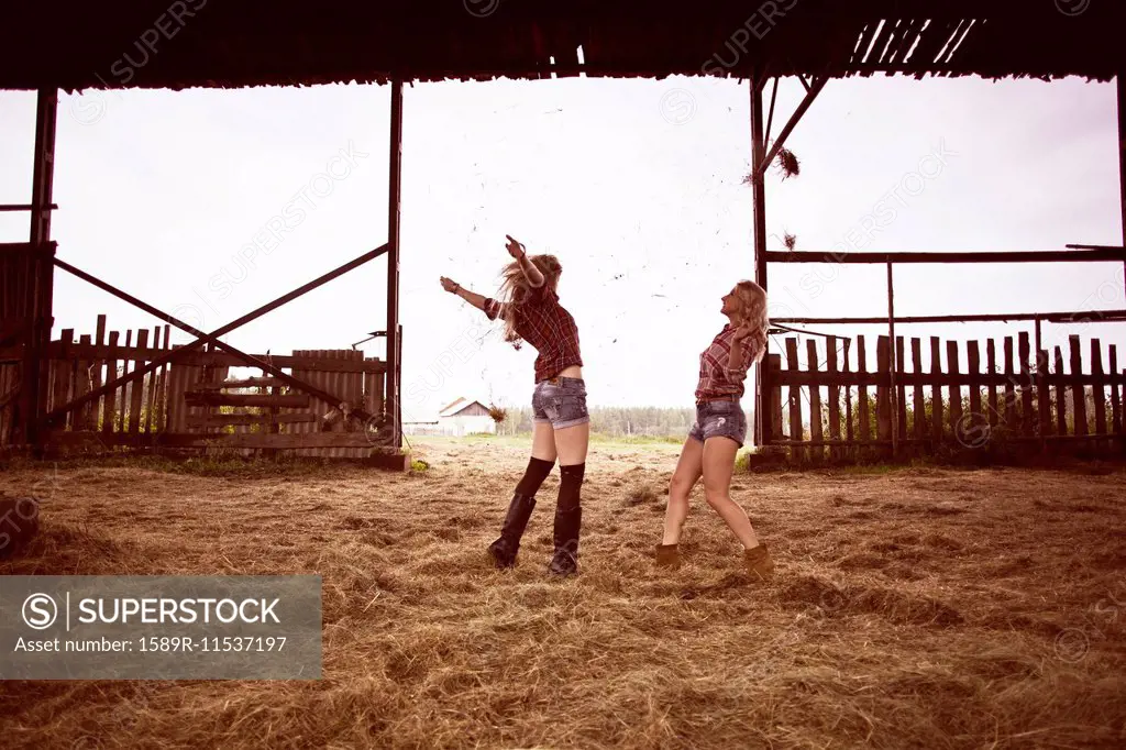 Caucasian women playing in hay in barn