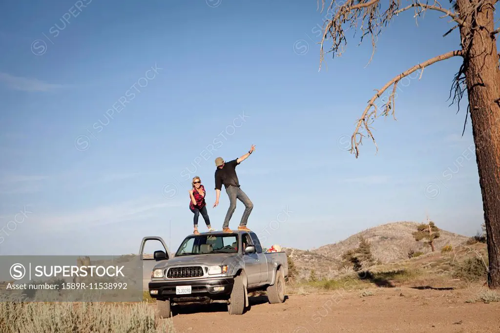 Caucasian couple standing on roof of pickup truck