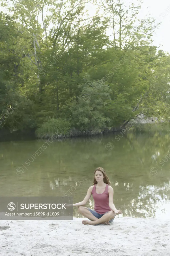 Woman in lotus position beside water