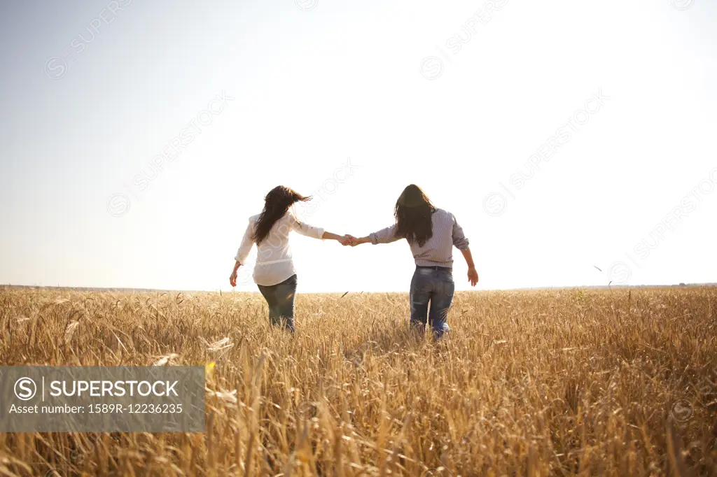 Caucasian women holding hands in rural field