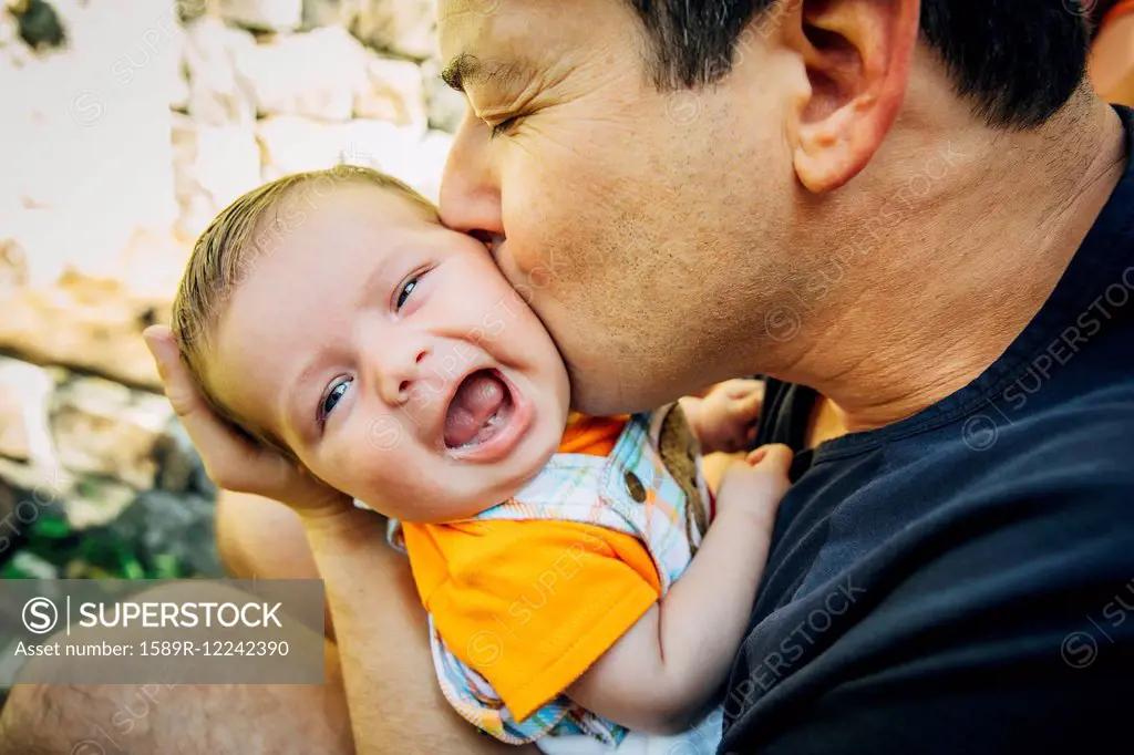 Caucasian father kissing baby boy outdoors
