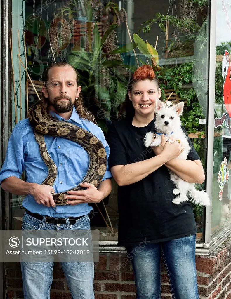 Caucasian couple holding pets outdoors