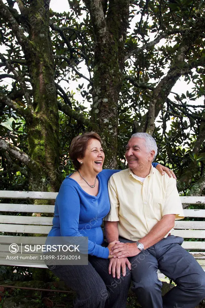 Senior Hispanic couple sitting on park bench
