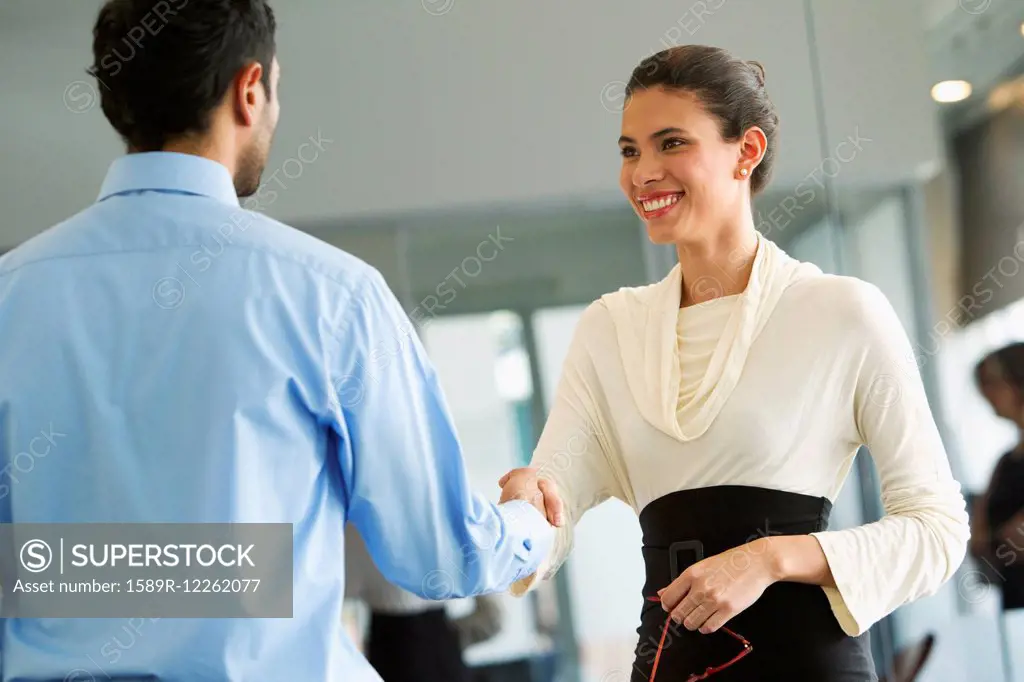 Hispanic business people shaking hands in office