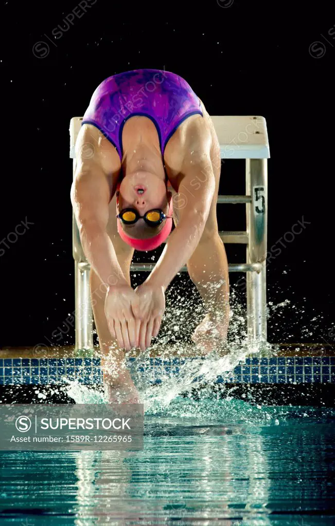 Caucasian swimmer diving off starting block