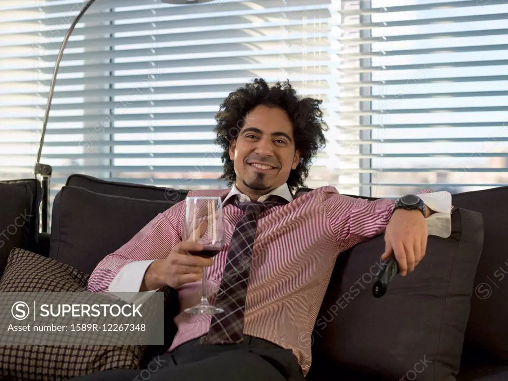 Middle Eastern man drinking red wine on sofa