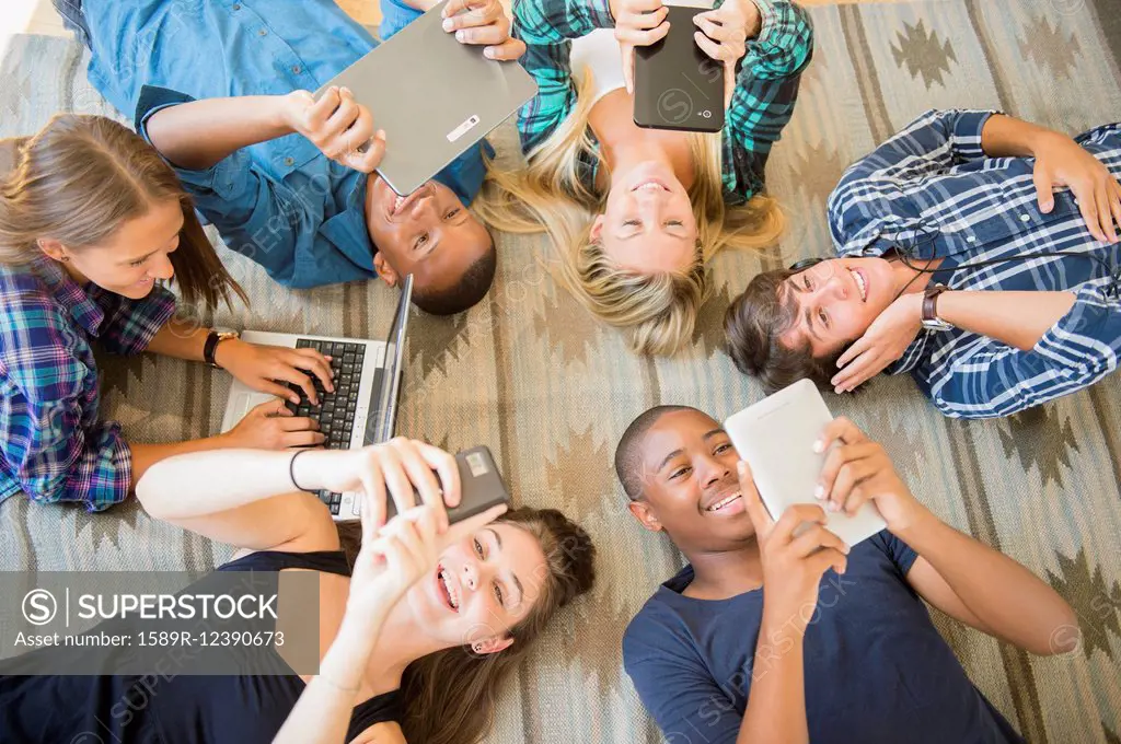 Teenagers laying on floor using technology