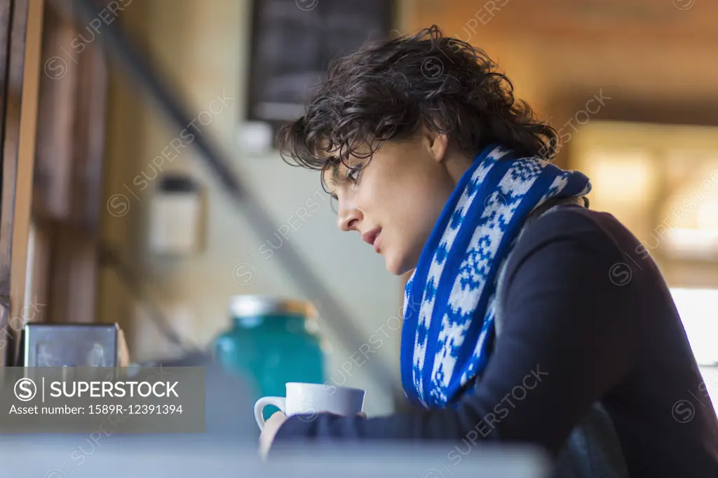 Mixed race woman drinking cup of coffee in cafe