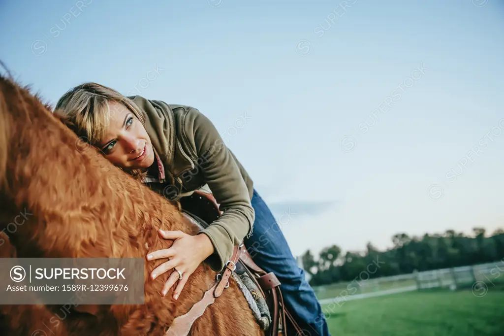 Caucasian woman riding horse on ranch