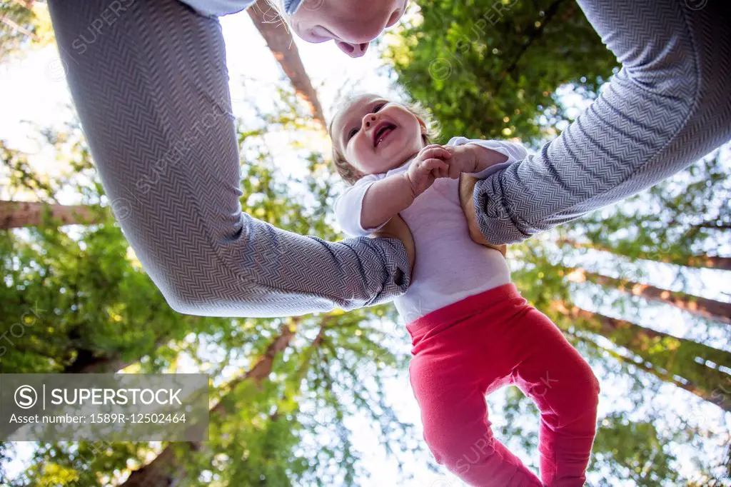 Low angle view of Caucasian mother playing with baby under trees