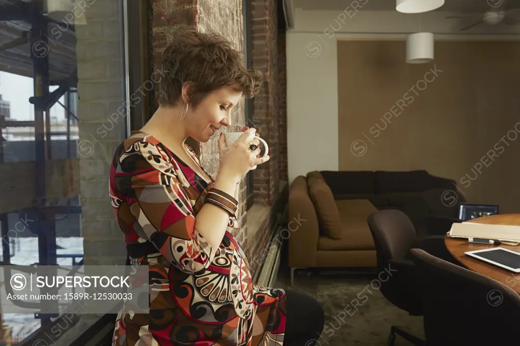 Pregnant businesswoman drinking coffee in office