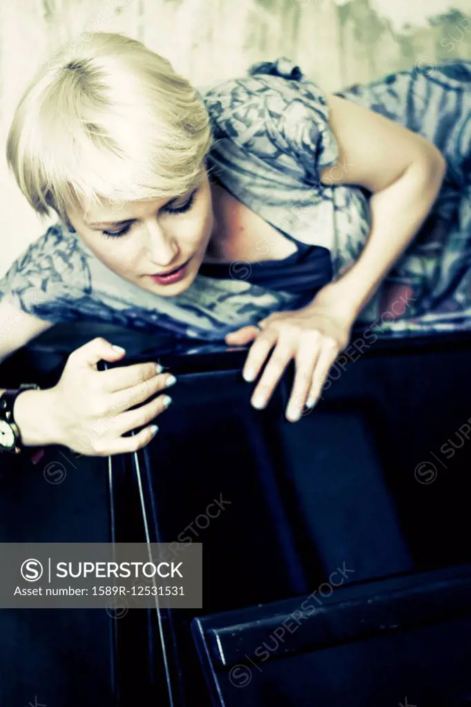 Caucasian woman laying on upright piano