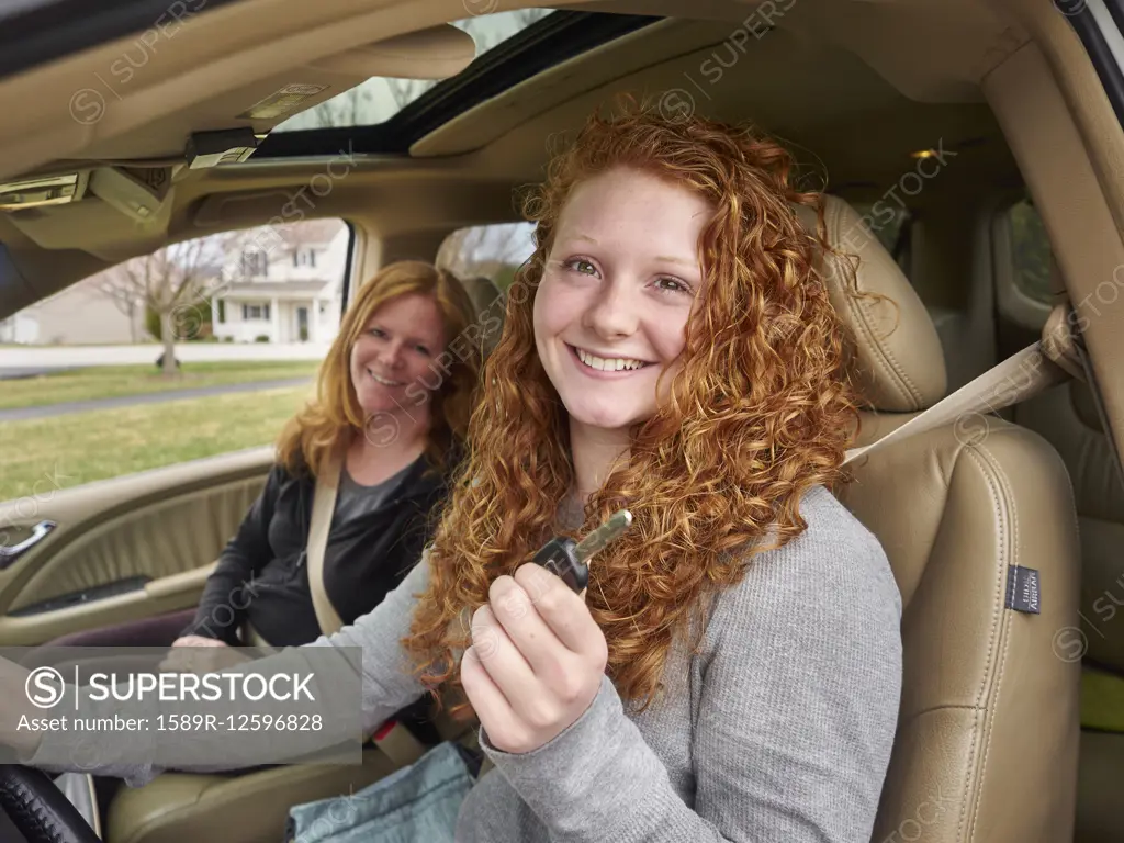 Caucasian teenage girl showing key with mother in car