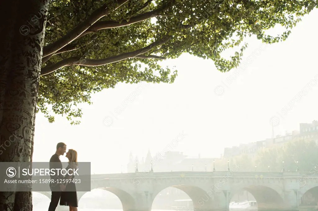 Caucasian couple kissing near bridge, Paris, Ile-de-France, France