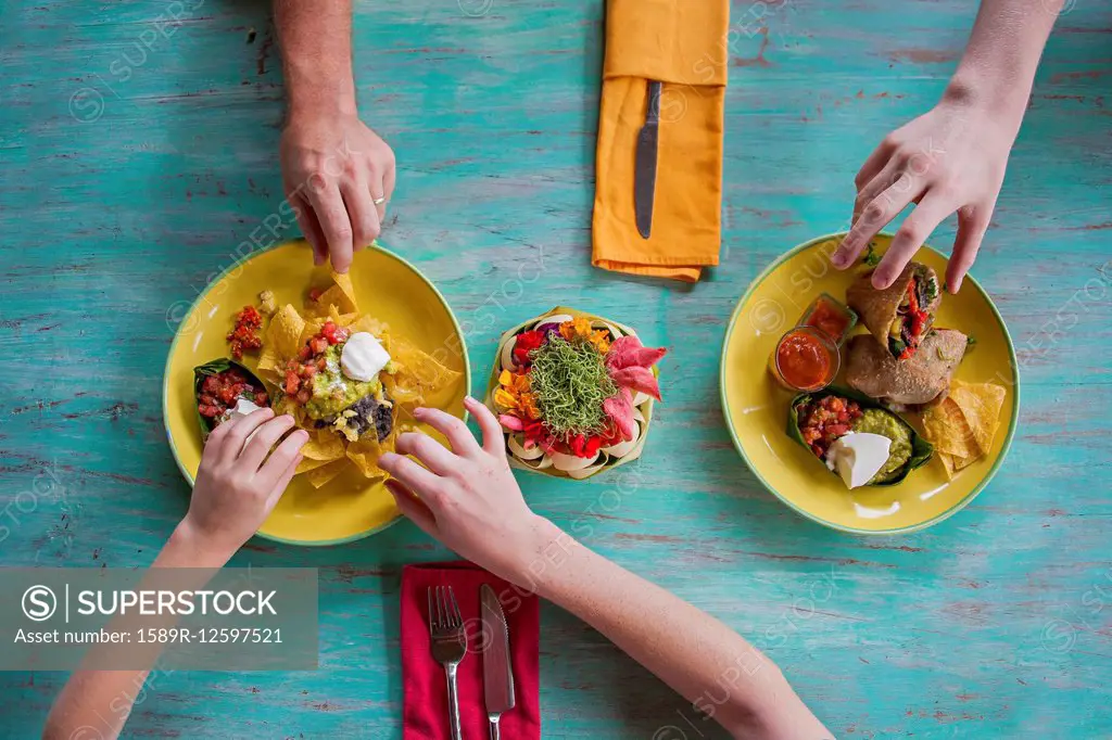 High angle view of hands reaching for food on plates