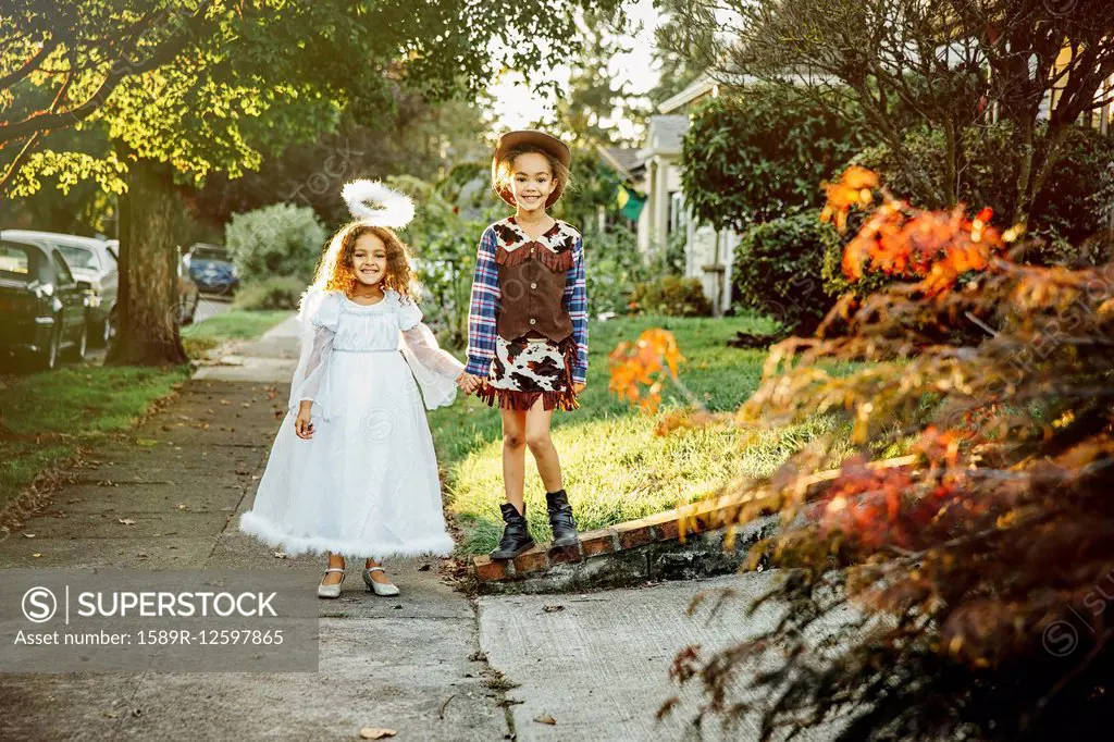 Sisters wearing Halloween costumes on sidewalk