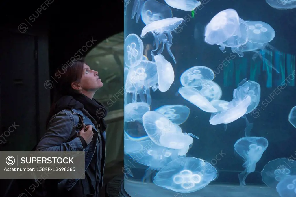 Caucasian woman admiring jellyfish in aquarium