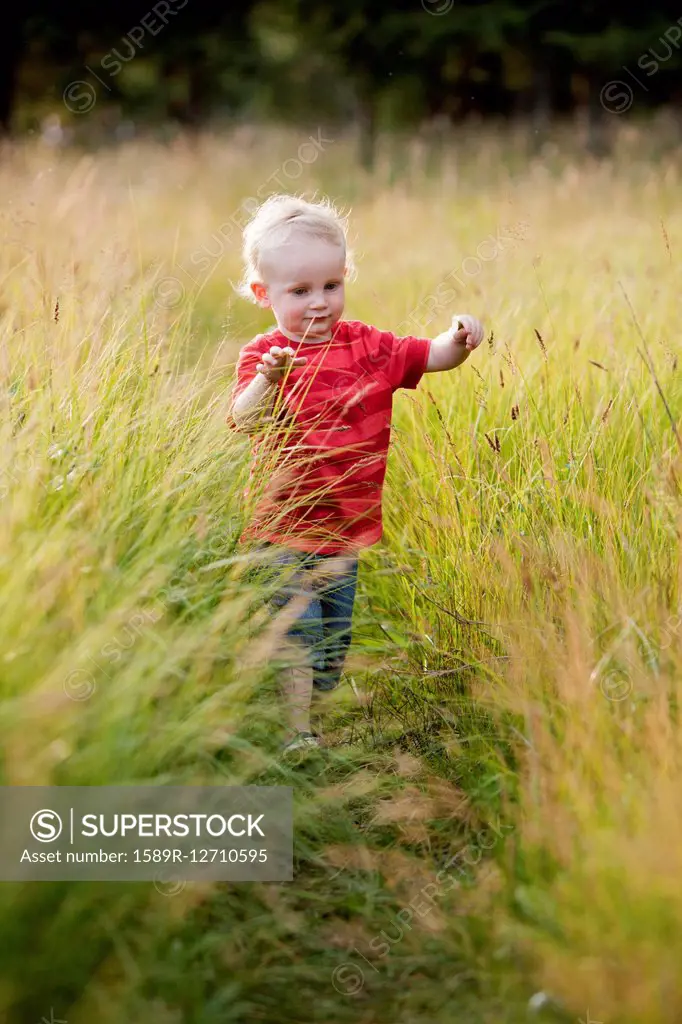 Caucasian boy playing in tall grass