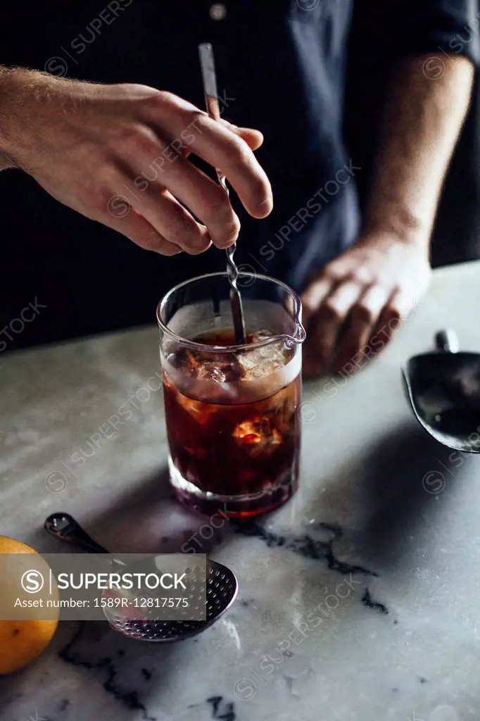 Caucasian bartender mixing cocktail in glass