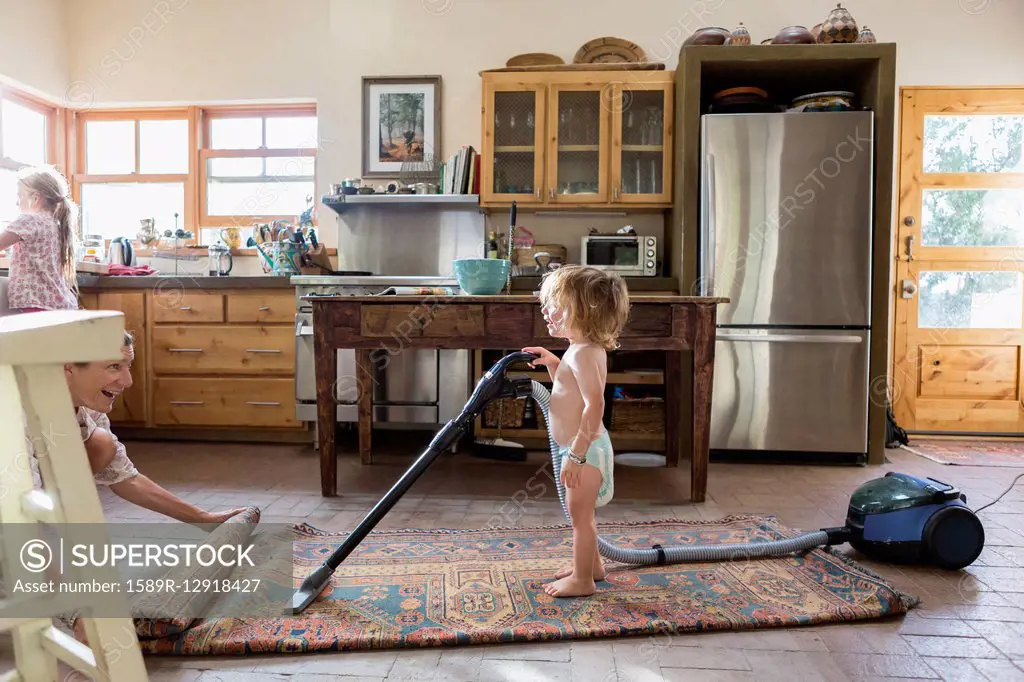 Caucasian brother and sister vacuuming rug
