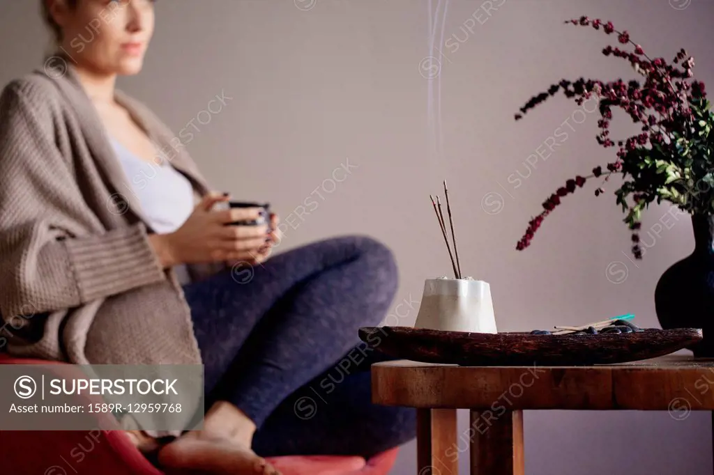Caucasian woman burning incense in living room