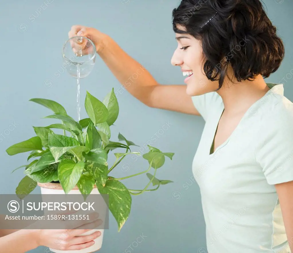 Hispanic woman watering plant