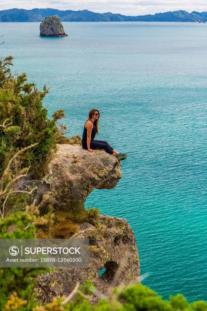 Caucasian hiker sitting on coastal cliff