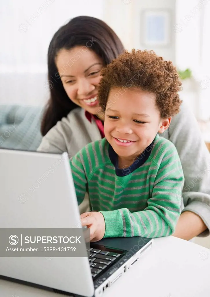 Mixed race mother using laptop with son