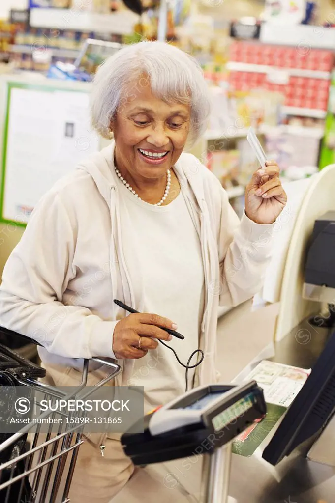 Senior African American woman paying with credit card in grocery store