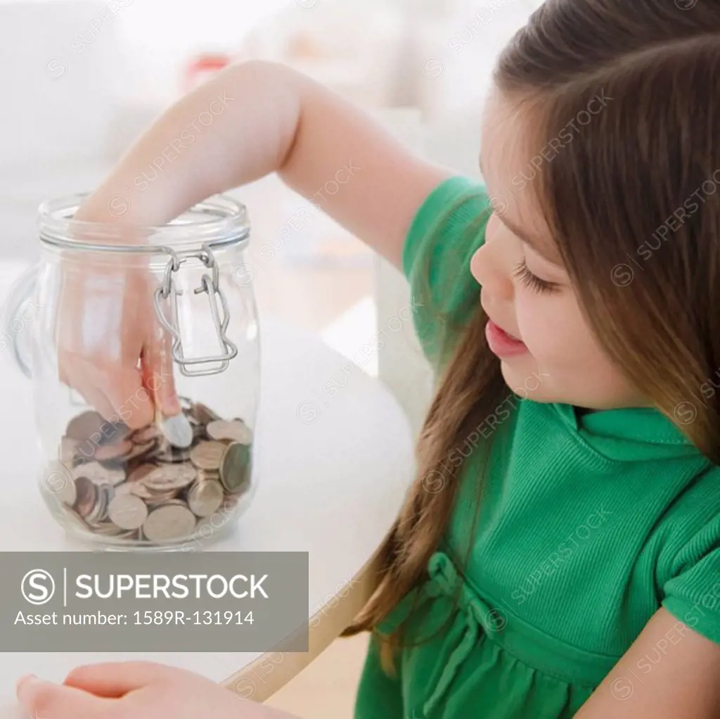 Mixed race girl taking coin out of jar