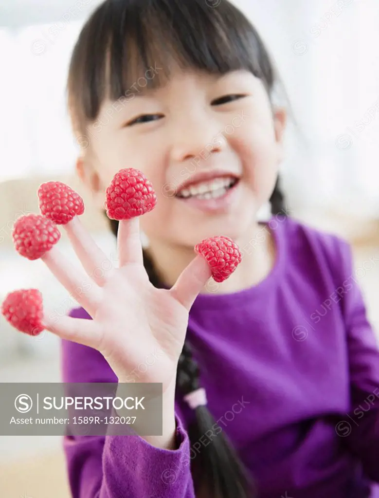 Chinese girl with raspberries on fingers