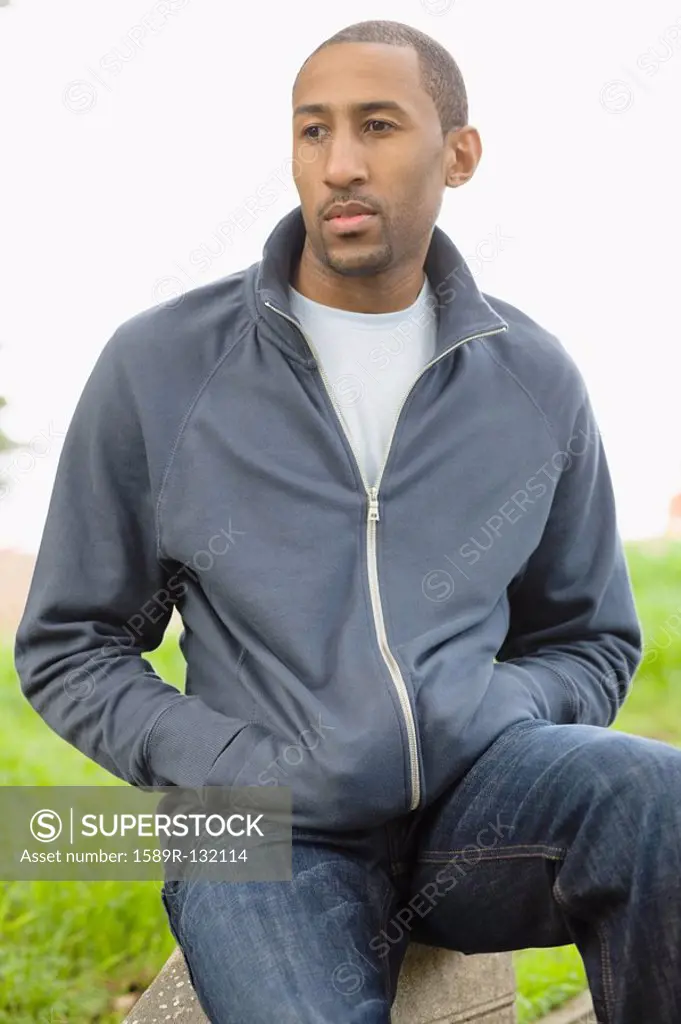 African American man sitting with hands in pockets