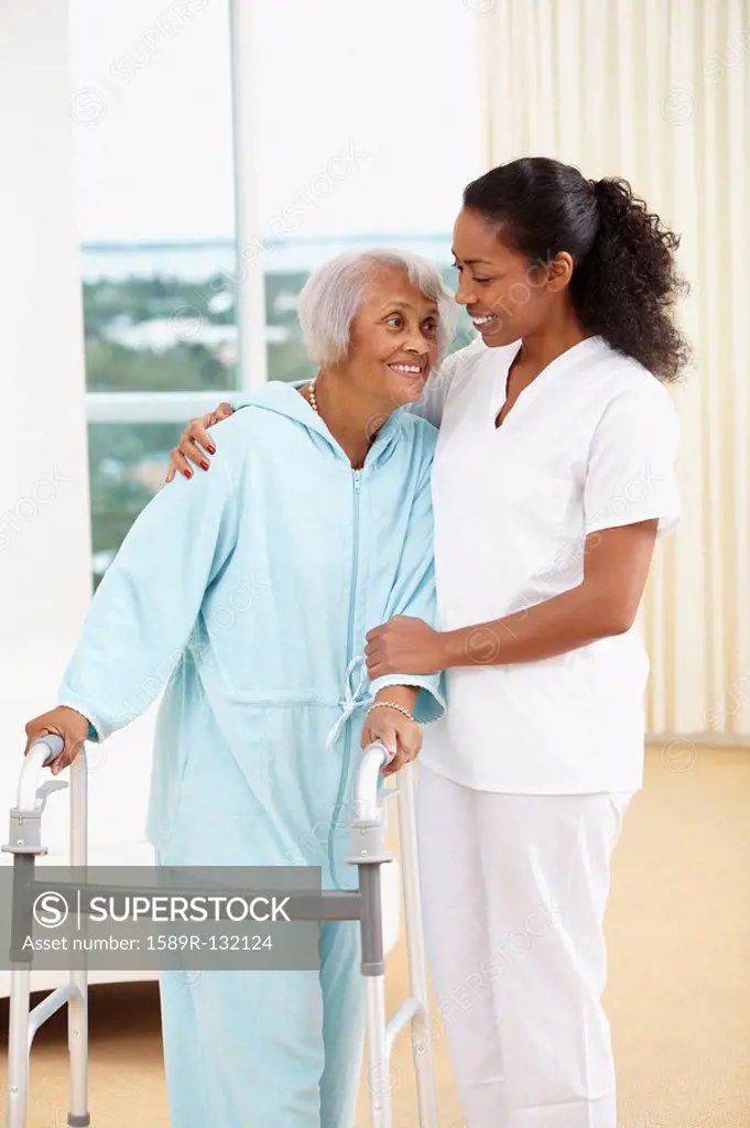 African American nurse helping senior woman with walker