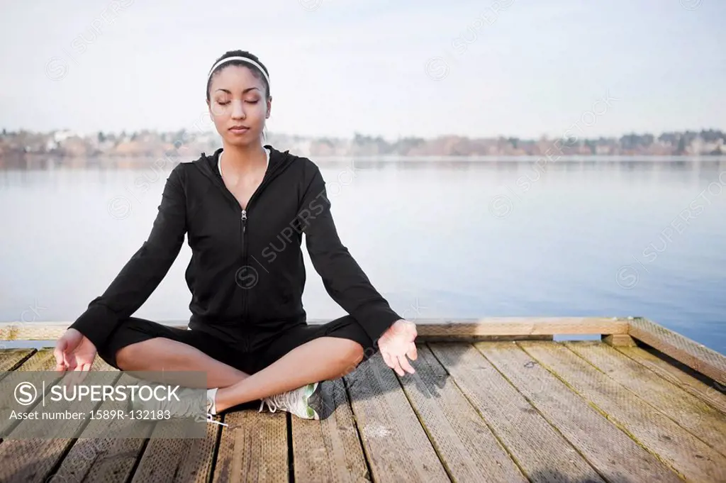 Mixed race woman practicing yoga on pier